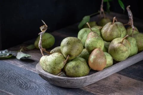 Group of rustic pears with stems and leaves on rustic farm table Stock Photos