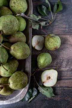 Group of rustic pears with stems and leaves on rustic farm table top view Stock Photos
