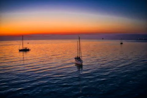 A group of sailboats before the sunrise, orange and violet sky Stock Photos