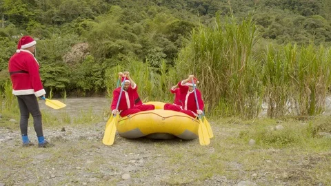 Group of santa claus warming up inside a rafting boat on shore Stock Footage 119650518