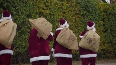 Group Of Santa Clauses Walking Down The Road, Back Shot Stock Footage 143719099