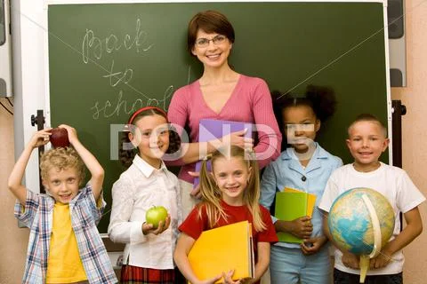 Group schoolchildren looking at camera with their teacher near by Stock Photos