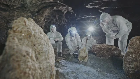 Group of scientists examining a crystal in a cave Stock Footage 103613269