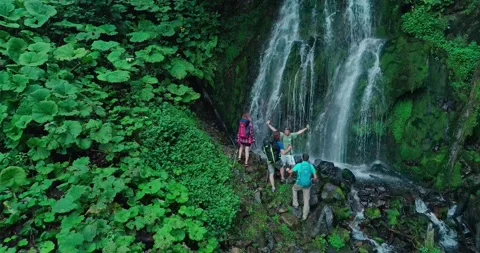 Group of scientists at foot of high mountain waterfall. Head of expedition Stock Footage 209126924