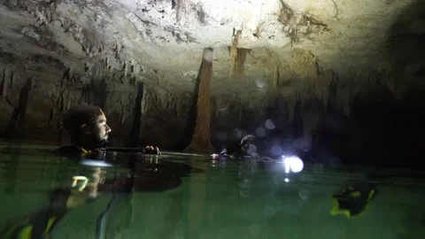 Group of scuba divers emerging in a dark underground cave with stalactites Vídeos de archivo 332002061
