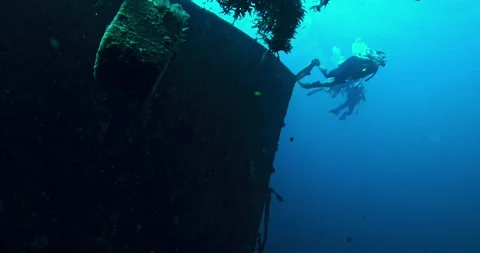 Group of scuba divers explores a massive shipwreck in deep blue water Stock Footage 327364707