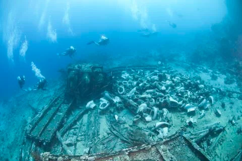 Group of scuba divers exploring the wrecked remains of a ship an Stock Photos