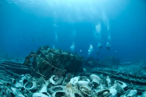 Group of scuba divers exploring the wrecked remains of a ship an Stock Photos