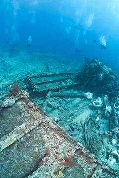 Group of scuba divers exploring the wrecked remains of a ship an Foto stock