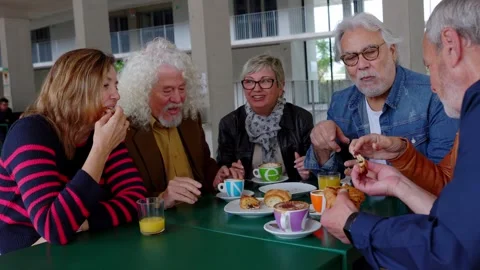 Group of senior people sitting at table enjoying breakfast in the morning Stock Footage 290144844