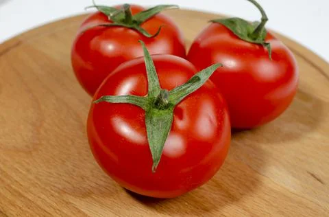 Group of several red tomatoes isolated on wooden board Foto stock