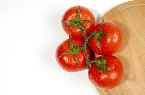 A group of several red tomatoes with moisture drops on a wooden cutting board Stock Photos
