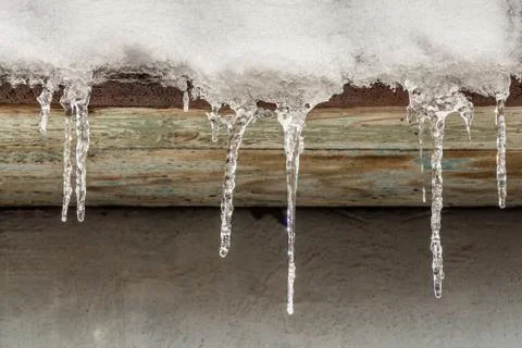 Group of sharp white and red transparent icicles is hanging down from the roo Stock Photos