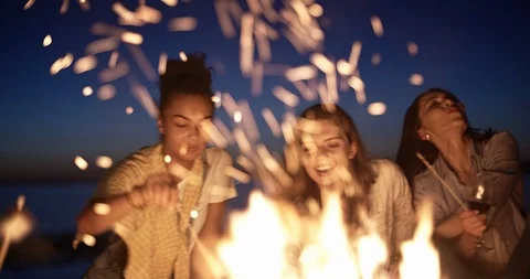 Group of six old multi-ethnic friends sitting near bonfire, roasting sausages Stock Footage 96460023