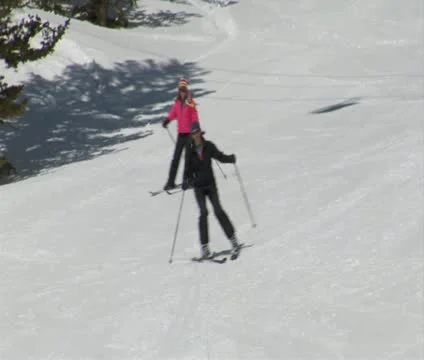 Group of skiers glide down easy hill, pass camera Stock Footage 21673396