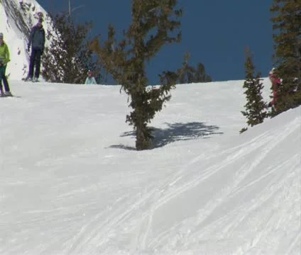 A group of skiers glide down hill on blue-sky day Stock Footage 21673554