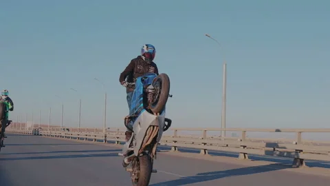 A group of skilled motorcyclists simultaneously ride on the rear wheel at the Stock Footage 105012930