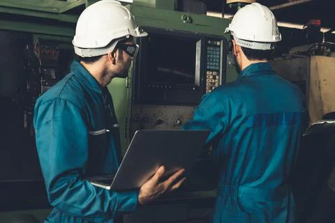 Group of skillful factory workers using machine equipment in workshop Foto stock