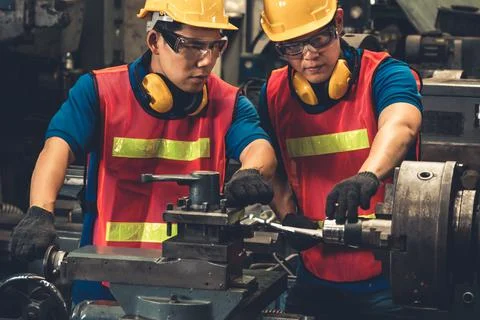 Group of skillful factory workers using machine equipment in workshop Stock Photos