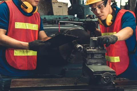 Group of skillful factory workers using machine equipment in workshop Stock Photos