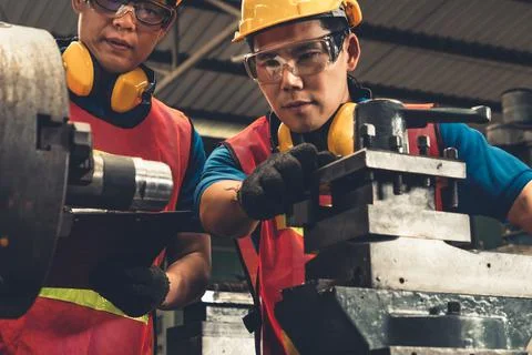 Group of skillful factory workers using machine equipment in workshop Stock Photos