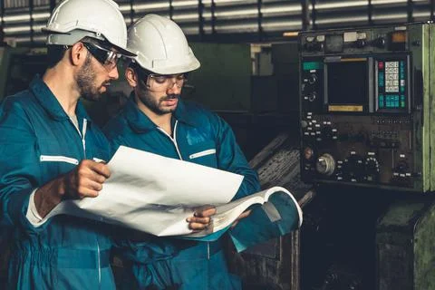 Group of skillful factory workers using machine equipment in workshop Stock Photos