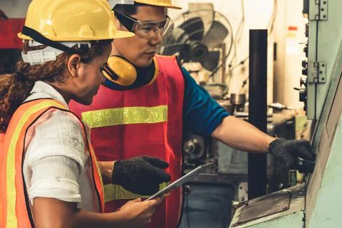 Group of skillful workers using machine equipment in factory workshop Stock Photos