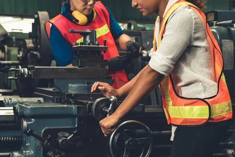 Group of skillful workers using machine equipment in factory workshop Stock Photos