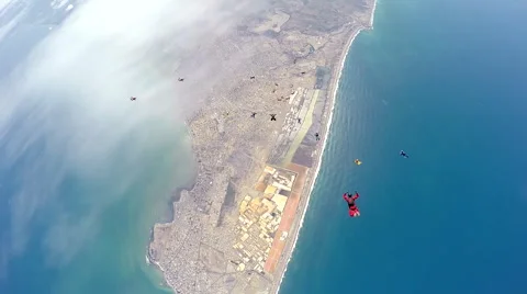 Group of skydivers are hovering in accelerated free fall above coastal city Video stock 60840606