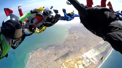 Group of skydivers are hovering in accelerated free fall above coastal city Video stock 60840701