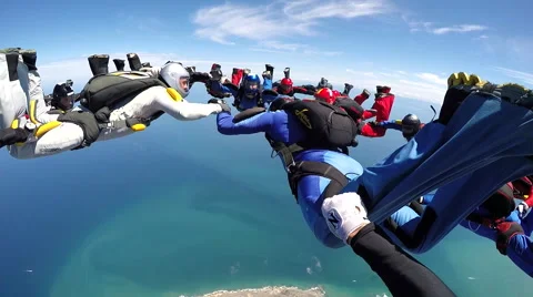 Group of skydivers are hovering in accelerated free fall above coastal city Video stock 60841247