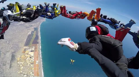 Group of skydivers are hovering in accelerated free fall above coastal city Video stock 60841466