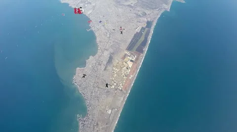 Group of skydivers are hovering in accelerated free fall above coastal city Video stock 60843015