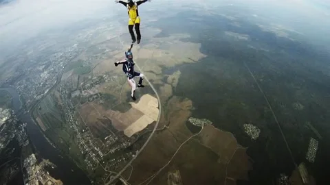 Group of skydivers flying in cloudy sky above green flatland. Extreme sport. Stock Footage 152064559