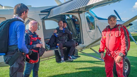 Group of skydivers prepares for the next jump on the ground in front of an Stock Footage 128737076