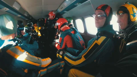 Group of skydivers sits inside a small plane awaiting a jump. Slow Motion Stock Footage 96578972