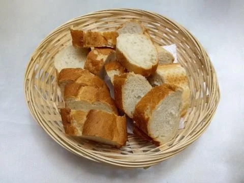 Group of sliced bread in a basket on white tablecloth Stock Photos