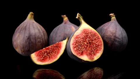 Group sliced figs lengthwise in half and quarter, isolated on black backgroun Stock Photos