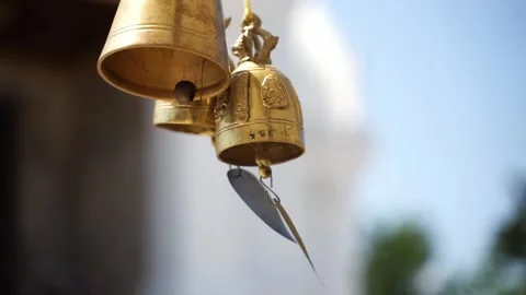 A group of small golden temple bells swaying in the wind against blue sky. 動画素材 336982619