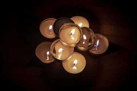 Group of small lit candles on a table Stock Photos