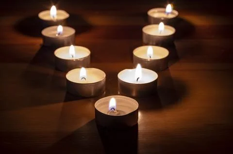 Group of small lit candles on a table Stock Photos
