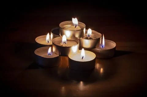 Group of small lit candles on a table Stock Photos