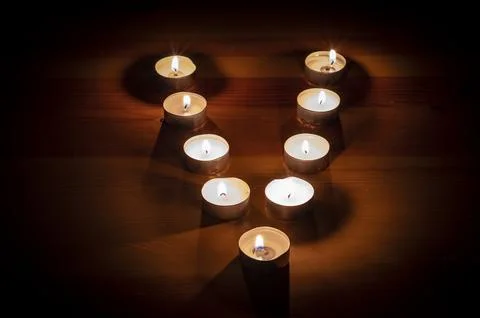 Group of small lit candles on a table Stock Photos