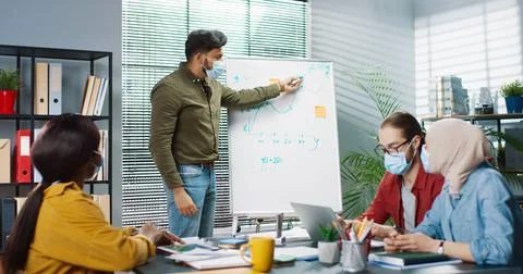 Group of smart young multinational colleagues in protective mask working in the Stock Photos