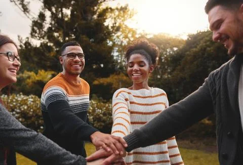 Group of smiling diverse friends stacking hands to express unity and support Stock Photos
