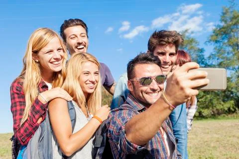 Group of smiling friends taking selfie with smartphone Stock Photos