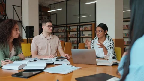 Group of smiling multicultural students studying and talking in library Stock Footage 250339565