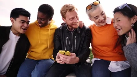 Group of Smiling people using mobile phone outdoors. Cheerful guys and girls Stock Footage 188016308