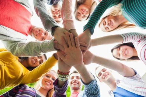 Group of smiling students putting hands in a circle on campus 写真素材