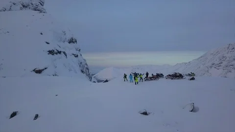 Group of snowmobile drivers stands on top of high mountain Stock Footage 112532346